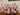 Group of people wearing matching pink shirts with a floral pattern in a casual setting.