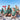 Family wearing Aussie Christmas Green matching outfits on the beach, showcasing festive shirts with Santa, candy canes, and native flora.