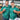 Two men wearing matching green patterned shirts in a warehouse setting.
