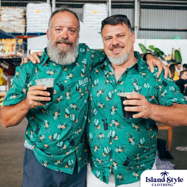 Two men wearing matching green patterned shirts in a warehouse setting.