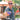 Man holding two colorful cocktails outdoors, wearing sunglasses and a patterned shirt.