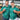 Two men wearing matching green patterned shirts with 'Island Style Clothing' logo, holding drinks in a warehouse setting.