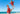 Man and child in matching red Hawaiian shirts on a beach with blue sky and ocean.