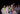 Group of people wearing festive attire with leis and sunglasses at night.