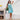 Christmas Pool Party women's dress featuring aqua blue fabric with Santa and cocktail motifs, styled for summer festivities.