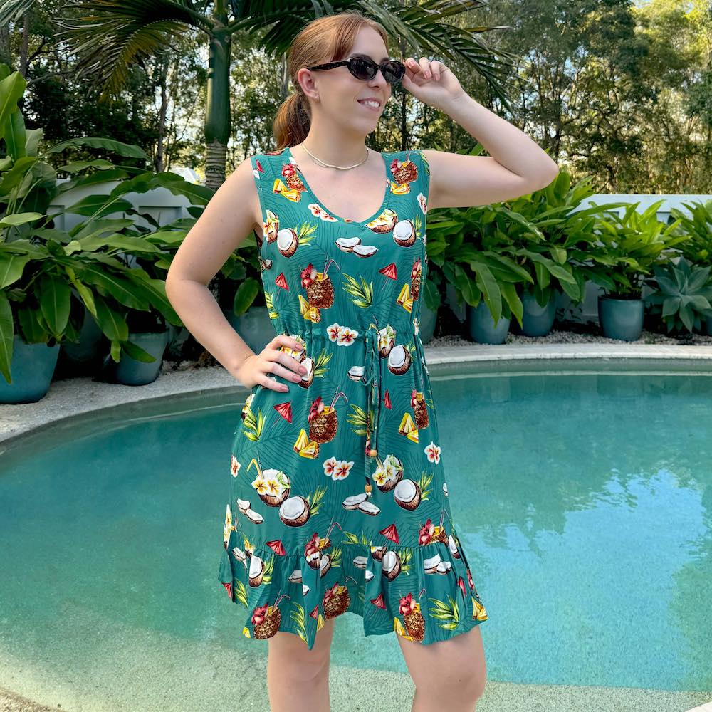 Unleash your playful side with our Coco Crush Hawaiian Dress! Made from soft rayon, this dress exudes tropical vibes with a v-neckline, non-elastic waist tie, and a ruffled hem. Its fun print featuring coconuts and pineapples on a teal base will transport you to an island paradise.