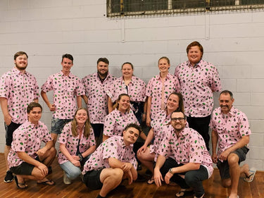 Group of people wearing matching pink shirts with a floral pattern in a casual setting.