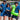 Three people in matching blue uniforms holding drinks and an inflatable crocodile on a beach.