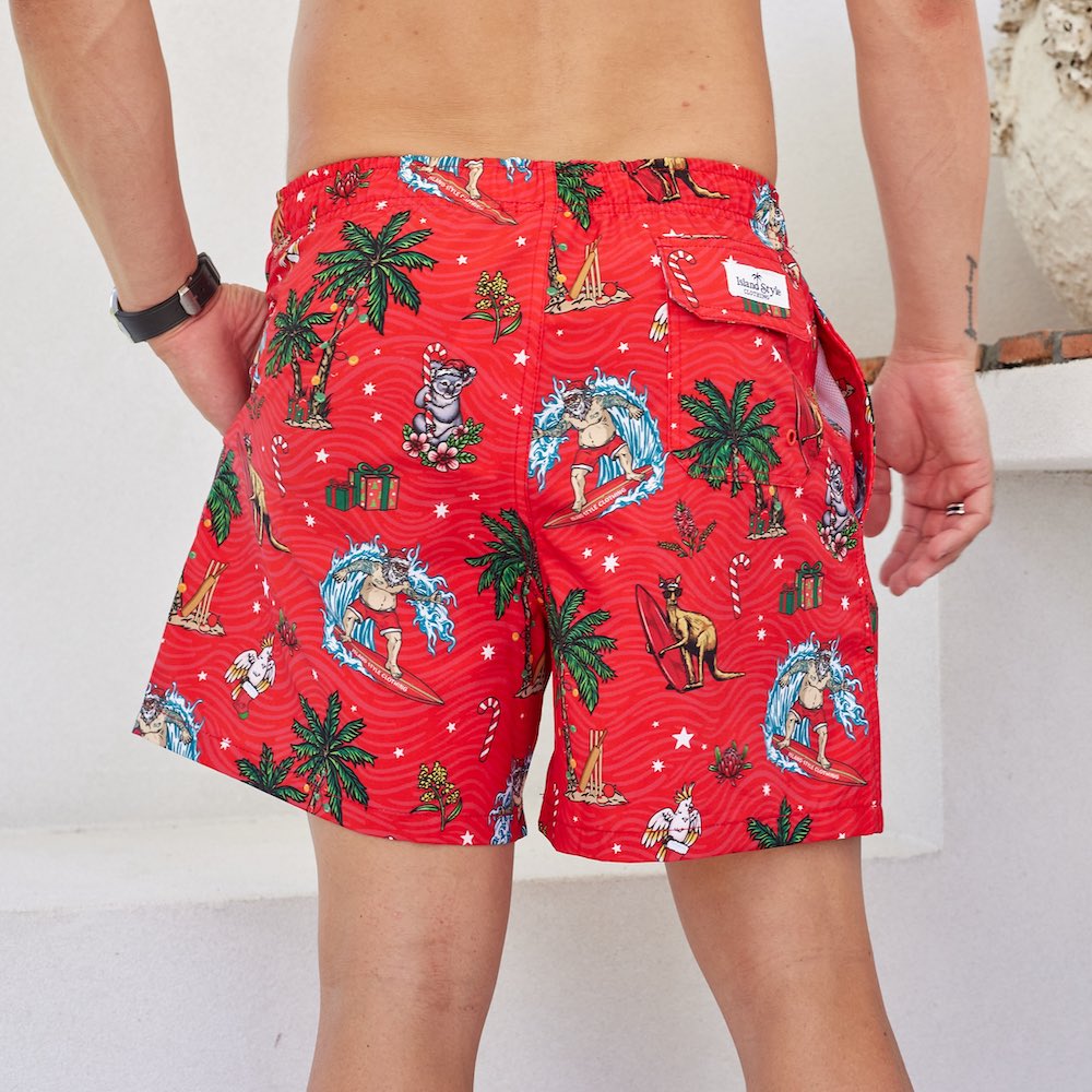 a man in red swim trunks with palm trees on them