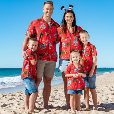 a family wearing matching red hawaiian Christmas shirts on the beach