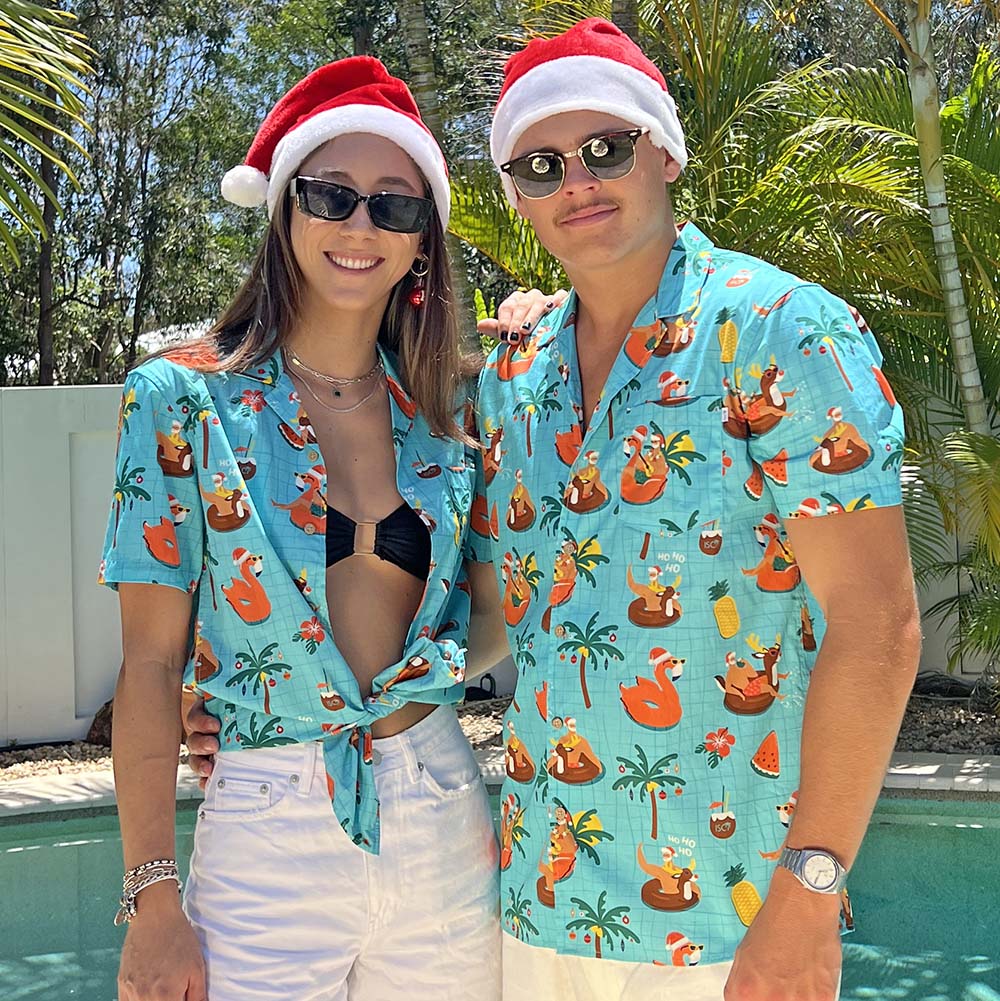 a man and a woman standing next to a pool in Christmas shirts