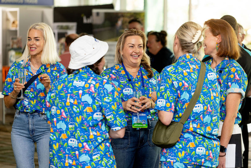 Group of women in matching blue scrubs with a pattern, standing together in an indoor setting.