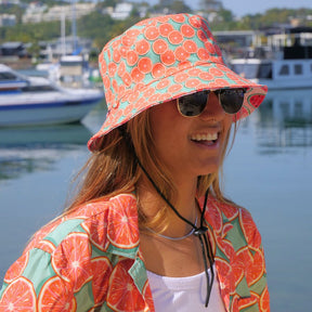 Bringing you the perfect way to top off your show-stopping Festival 'fit. Get two for the price of one with our reversible bucket hats. One side is our Groovy Grapefruit and the other side is our Shake Ya Melons. Pimm's o'clock is approaching; you pour, we've prepped the fruit. Level up the look with the Matching Mens or Unisex Shirts Groovy Grapefruit Reversible design - Shake Ya Melons on the flipside 100% Polyester Brim width - 6cm