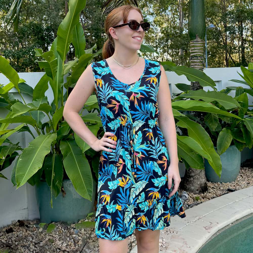 Unleash your playful side with our Jungle Fever Hawaiian Dress! Made from soft rayon, this dress exudes tropical vibes with a v-neckline, non-elastic waist tie, and a ruffled hem. Its fun print featuring tropical leaves and bird of paradise on a black base will transport you to an island paradise.