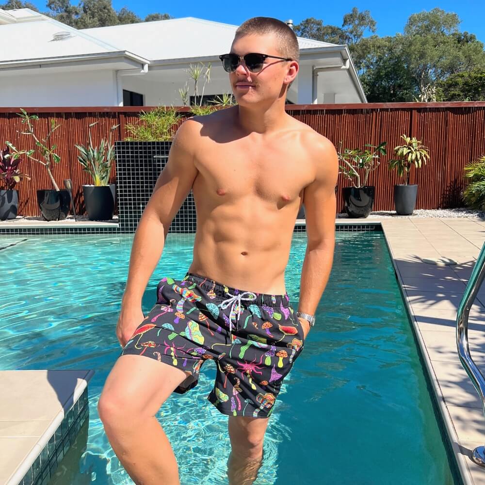 a man standing in a pool wearing swim trunks