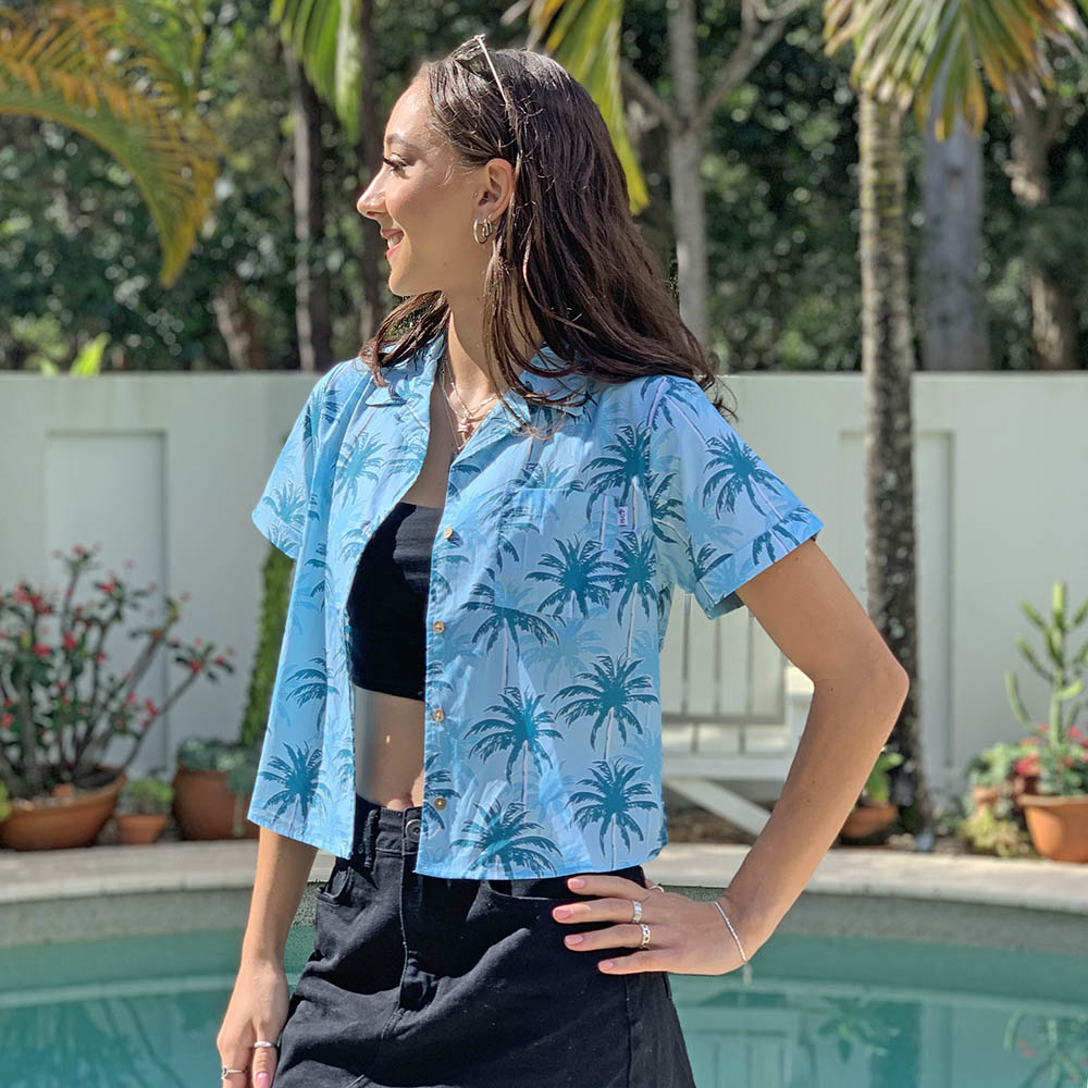 Our Island Blues crop shirt is essential for having a sunny Aussie summer! Made with 100% cotton, it features an allover print of palm trees in blue tones – perfect for a casual laidback look and great for uniforms. Enjoy the heat without sweating it!