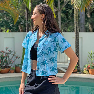 Our Island Blues crop shirt is essential for having a sunny Aussie summer! Made with 100% cotton, it features an allover print of palm trees in blue tones – perfect for a casual laidback look and great for uniforms. Enjoy the heat without sweating it!